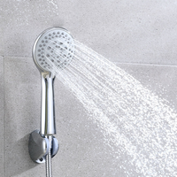 Chrome handheld shower head spraying water in a gray tiled shower